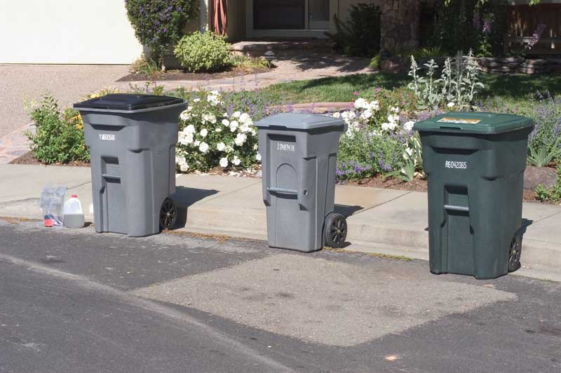 Residential garbage, recycling, and compost collection carts on a street shown at three foot spacing