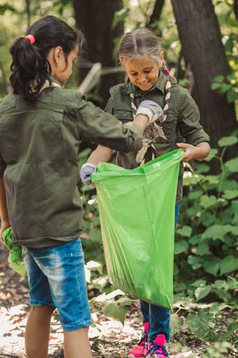 Groups of female students cleaning a park near their school to help keep it green
