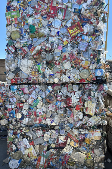Cubes of crushed tin cans outside a warehouse door at a recycling center